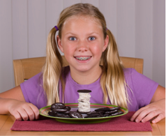 A child sitting at a table with a plate of cookies